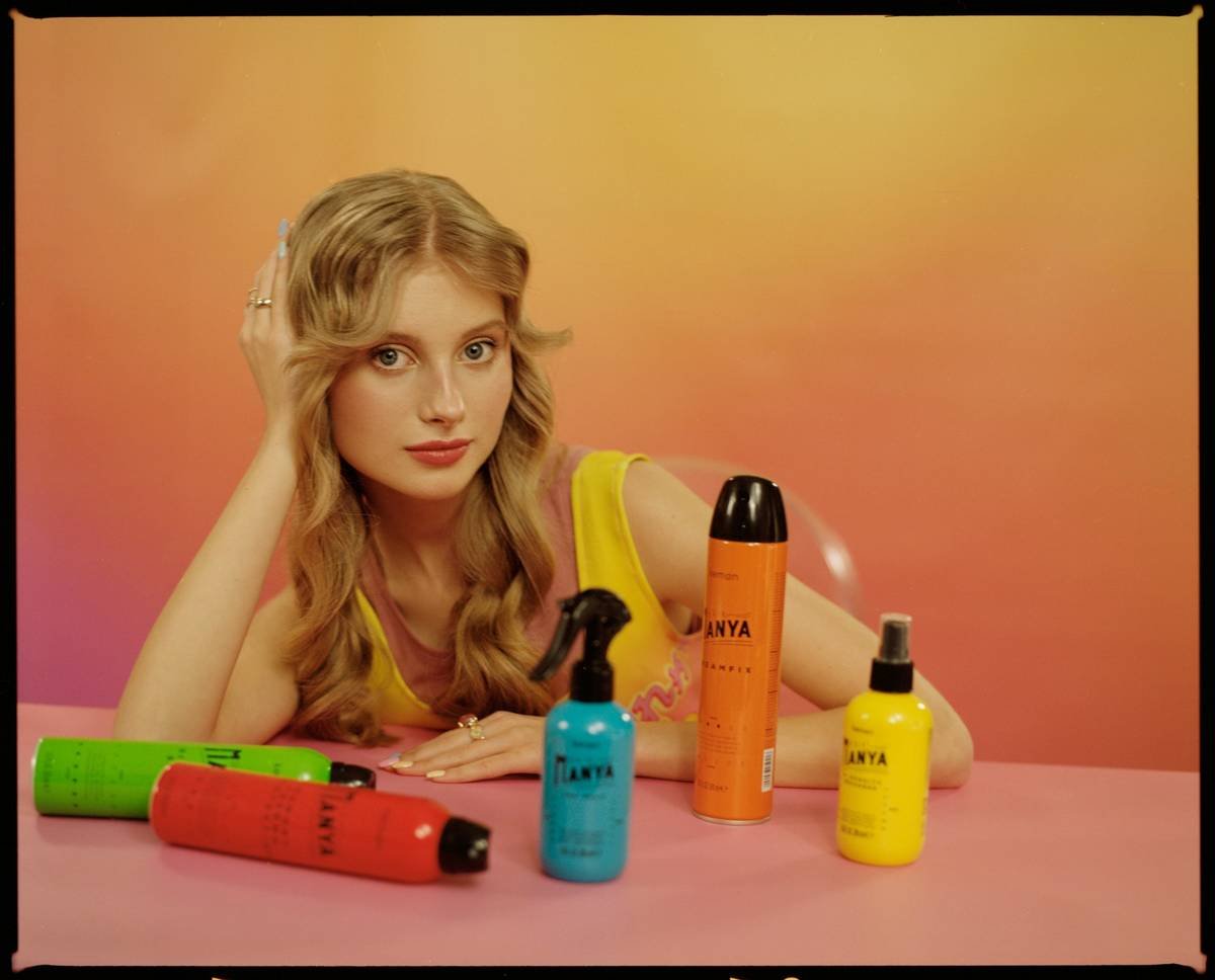Stylist applying texturizing spray under lifted hair sections before inserting pins